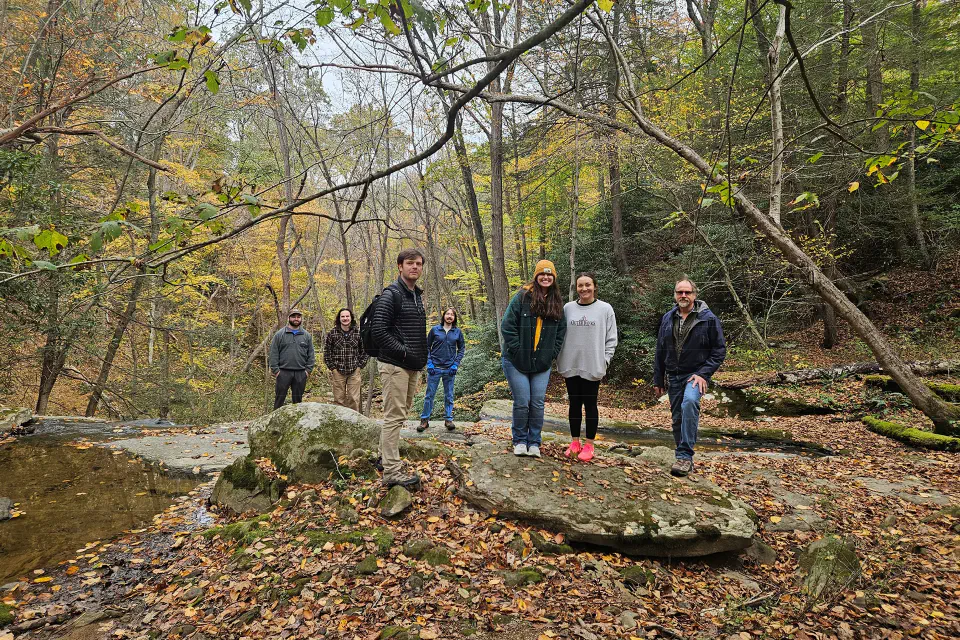 WVU Law students in the woods with fallen leaves on the ground.